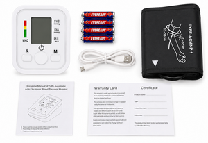 Blood pressure monitor with cuff, batteries, USB cable, and documentation on a white background