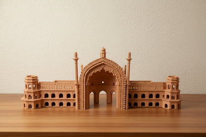 A small wooden architectural model of Rumi Darwaja, Lucknow a domed palace or mosque with minarets, displayed on a wooden table in an indoor room.